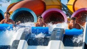 three friends sliding down Kowabunga Racer ride at Big Kahuna's in Destin, Florida, USA